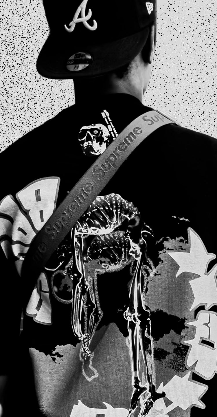 Model facing away, wearing KIBISHI’s bold graphic tee with skeleton and graffiti artwork — homepage visual showcasing artistic streetwear rooted in culture and statement design.