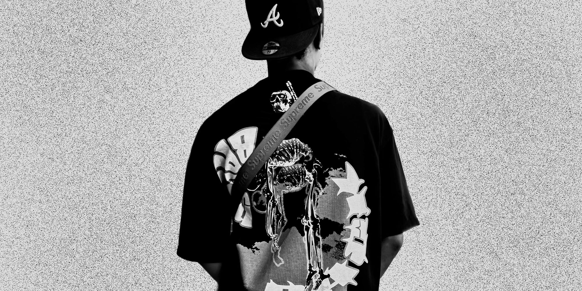 Model facing away, wearing KIBISHI’s bold graphic tee with skeleton and graffiti artwork — homepage visual showcasing artistic streetwear rooted in culture and statement design.