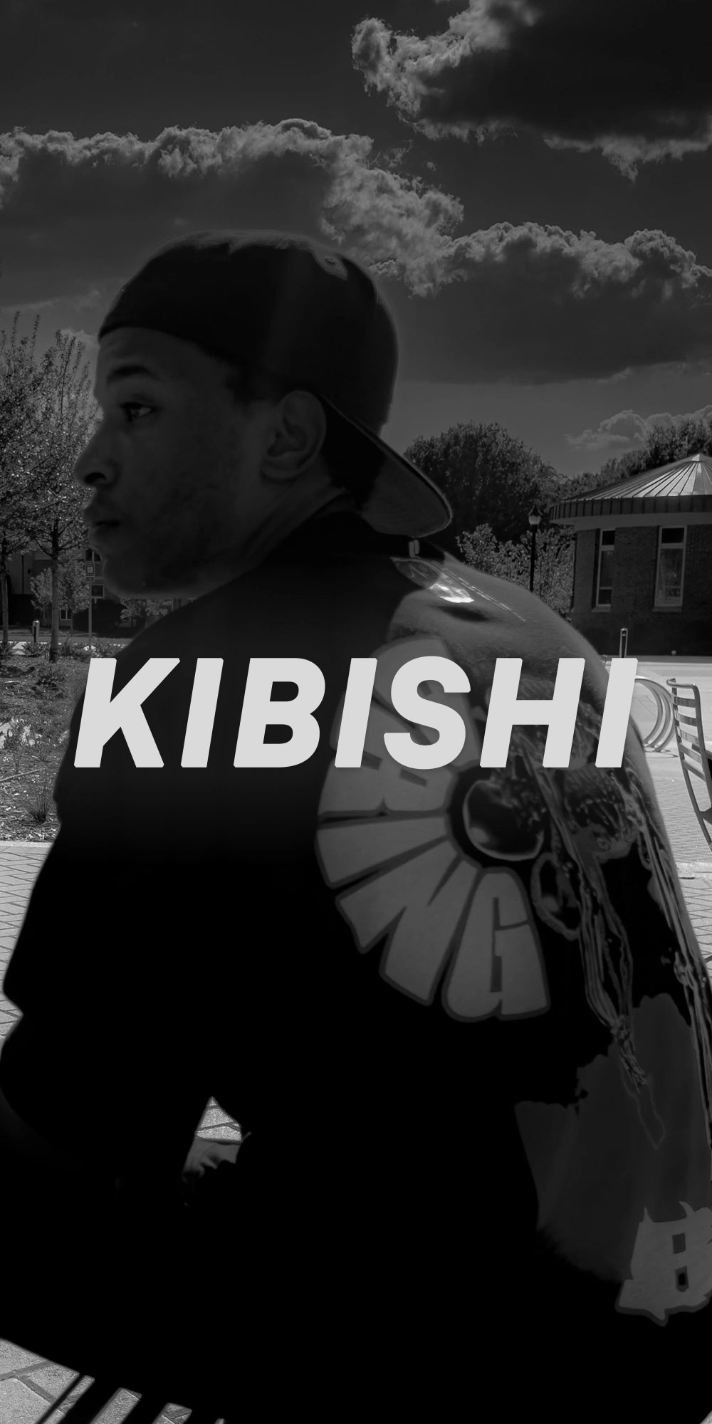 Black and white photo of a male model in oversized streetwear t-shirt with bold back print from KIBISHI, an artistic and inclusive streetwear brand.